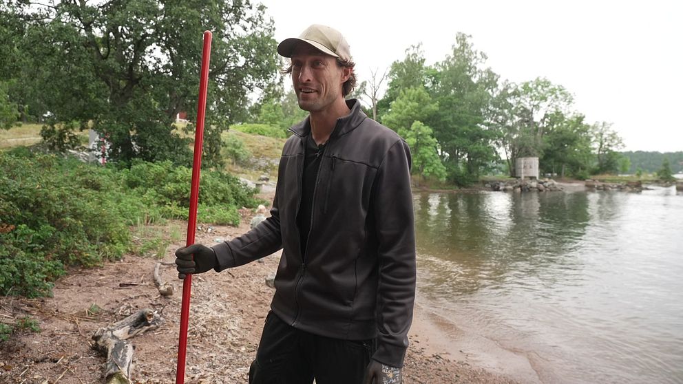 Christoffer städar bort skräp från stranden.