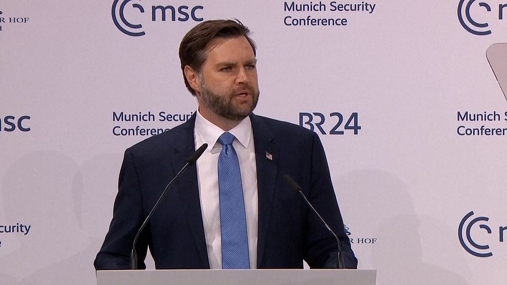 En man iklädd kostym står vid ett podium på München säkerhetskonferens, med logotyper för MSC och BR24 synliga i bakgrunden.
