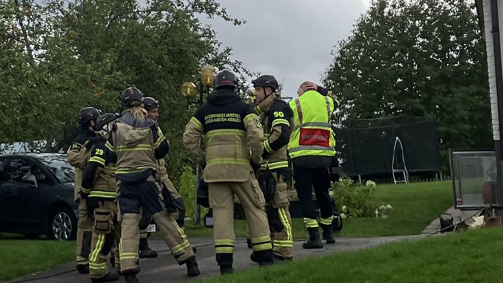 Flera personer ur räddningstjänsten står i en klunga vid en villa.