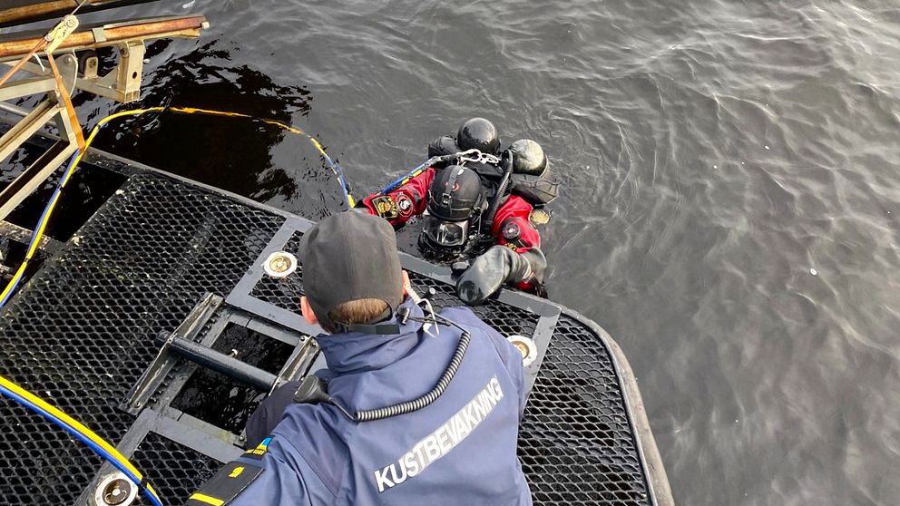 En kustbevakare hjälper upp en dykare i båten.