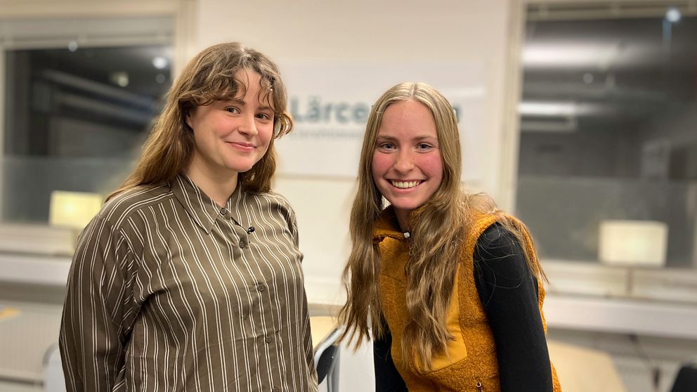 Emma Gunnarsson till vänster med brunt smålockigt hår och Maja Modig med långt hår och en fleeceväst, står i ett klassrum på campus Åre.