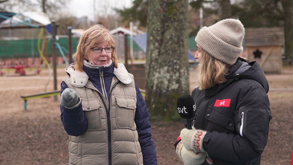 Kvinna i lekpark som pekar på ett av sina barnbarn.