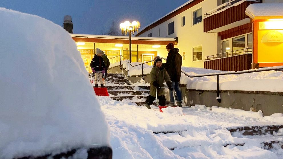 Fler barn iklädda vinterkläder skottar snö