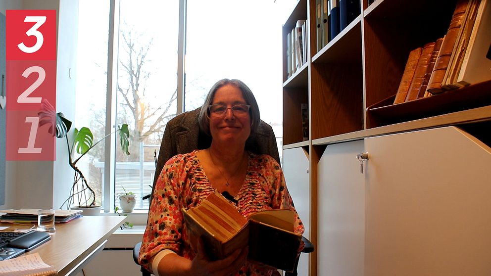 Åsa Granath, gruppchef på Uppsala Universitets stipendiekansli, sitter med en stor, gammal bok.