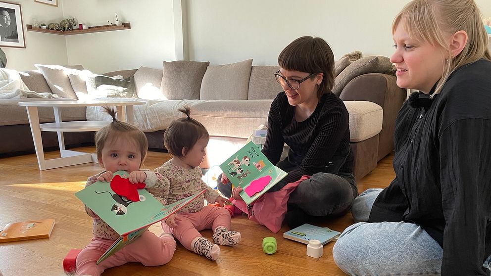 11-månaders tvillingar sitter på golvet med böcker