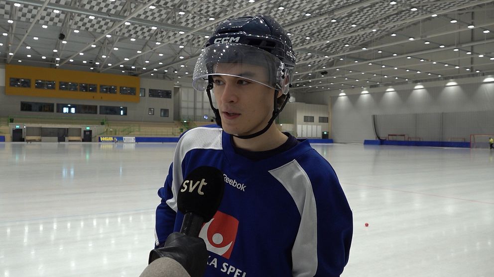 En person i bandyutrustning intervjuas på en isrink. Bakgrunden visar en stor, modern inomhuslokal.