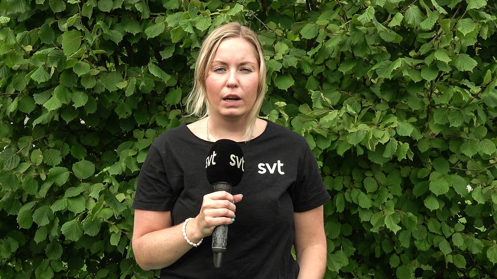SVT:s reporter Beatrice Emmerik står med en mikrofon i handen framför en buske.