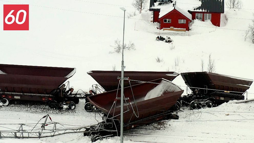 urspårade malmvagnar i vintermiljö, en röd stuga i bakgrunden