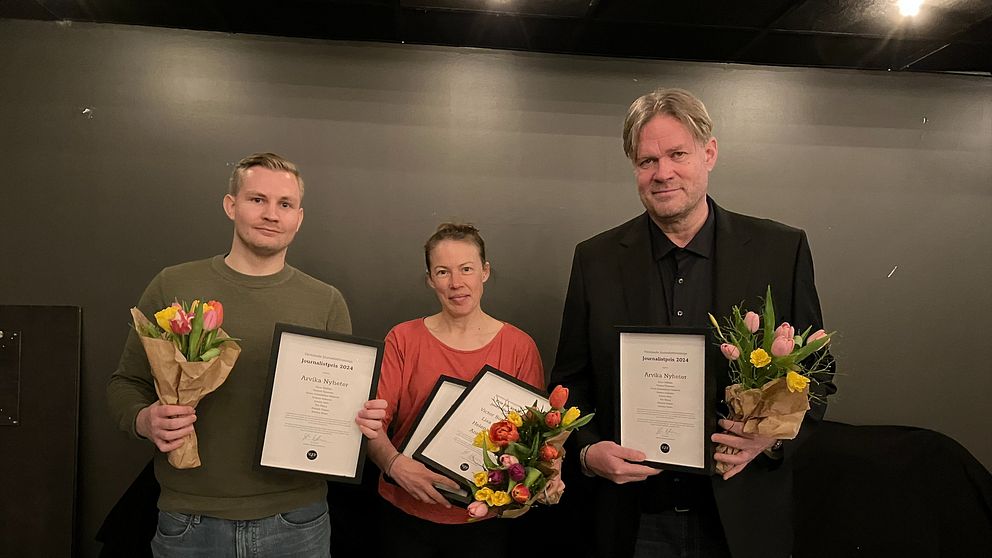 Tre personer håller diplom och blombuketter, stående bredvid varandra.