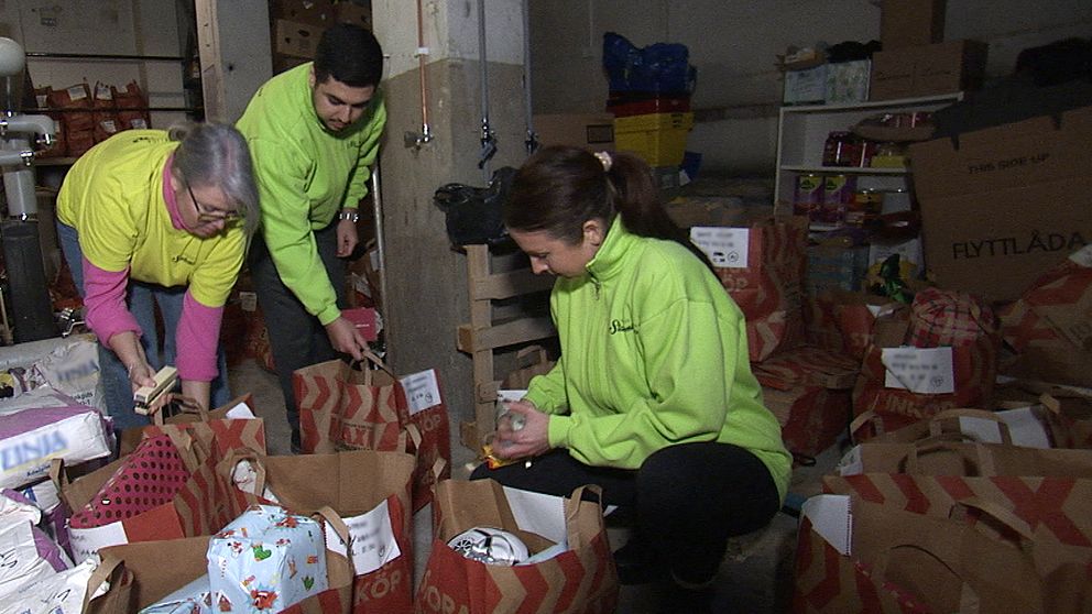 Tre personer som packar pappkassar med julklappar.