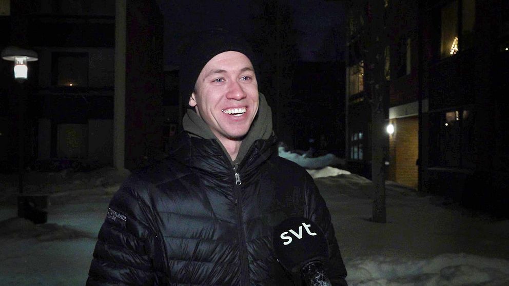Emil Persson, skidåkare står och ler i en svart dunjacka i ett bostadsområde.