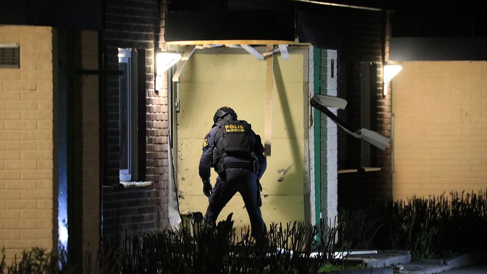 Polis på plats utanför en sprängd ytterdörr till bostadshus i Bro.