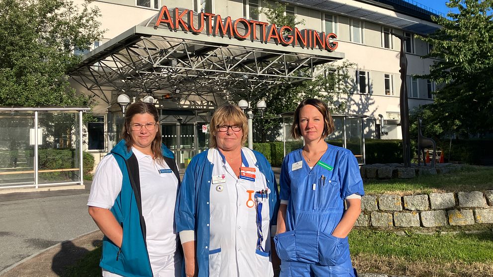 Tre sjuksköterskor i arbetskläder framför akutmottagningen på Akademiska sjukhuset i Uppsala.
