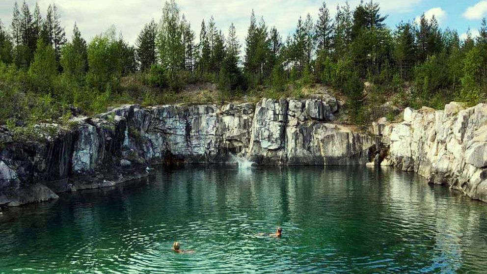 Tre personer badar i det smaragdfärgade vattnet i Norvijaur.