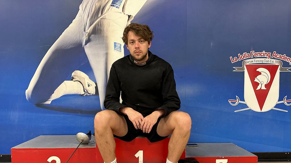 Fäktaren Konstantin Lokhanov, från Ryssland men som nu bor i USA, sittandes på en prispall i en fäkntingssal.