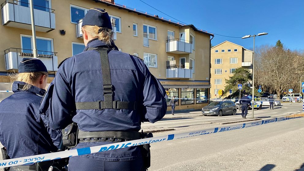 Två poliser med ryggen mot kameran, i bakgrunden bostadshus