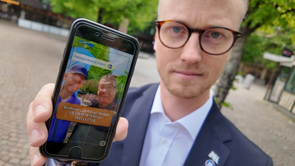Moderaten Andreas Löwenhöök håller upp en mobiltelefon och visar bild från ett videoklipp