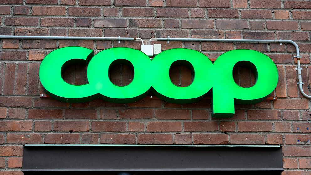 Grön Coop-skylt monterad på tegelvägg.