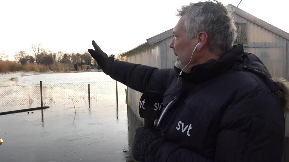 SVT:s reporter Per Lärka pekar ut över det översvämmade området vid Ringsjön.