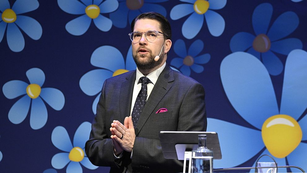 Jimmie Åkesson (SD) i talarstolen mot en bakgrund med partisymbolen