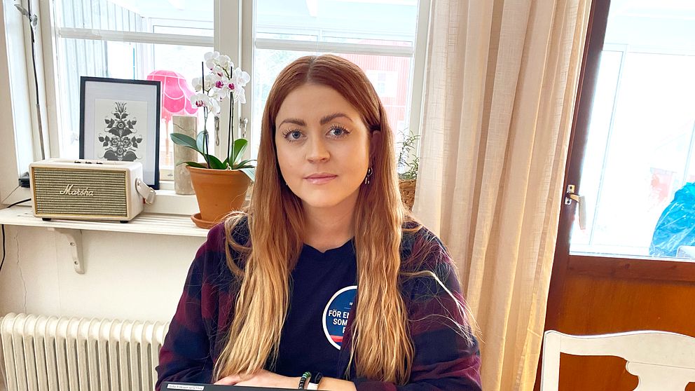en politiker vid ett köksbord och en laptop framför henne på bordet