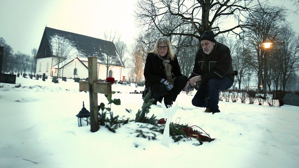 två personer sitter vid grav