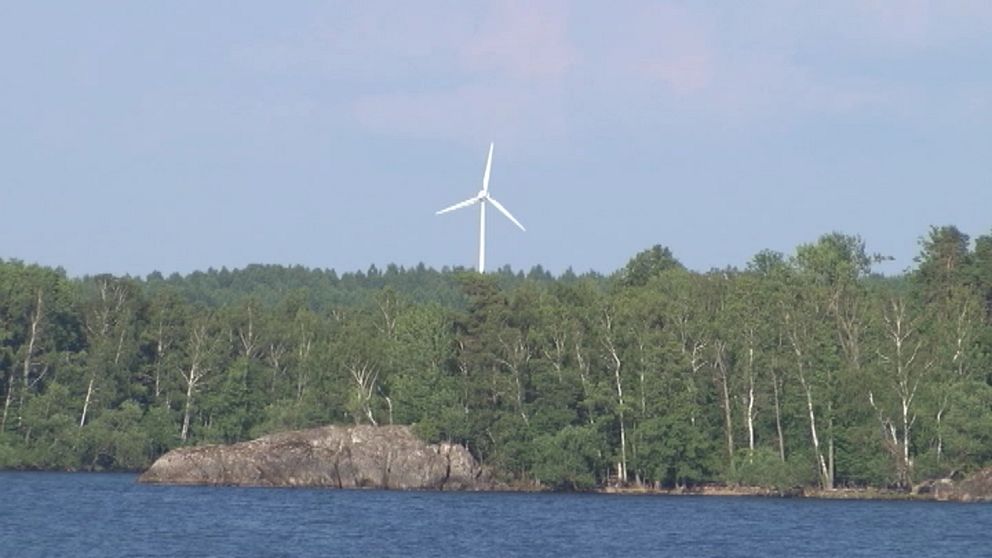 ett ensamt vindkraftverk i skogsområde sett från sjön Hjälmaren.