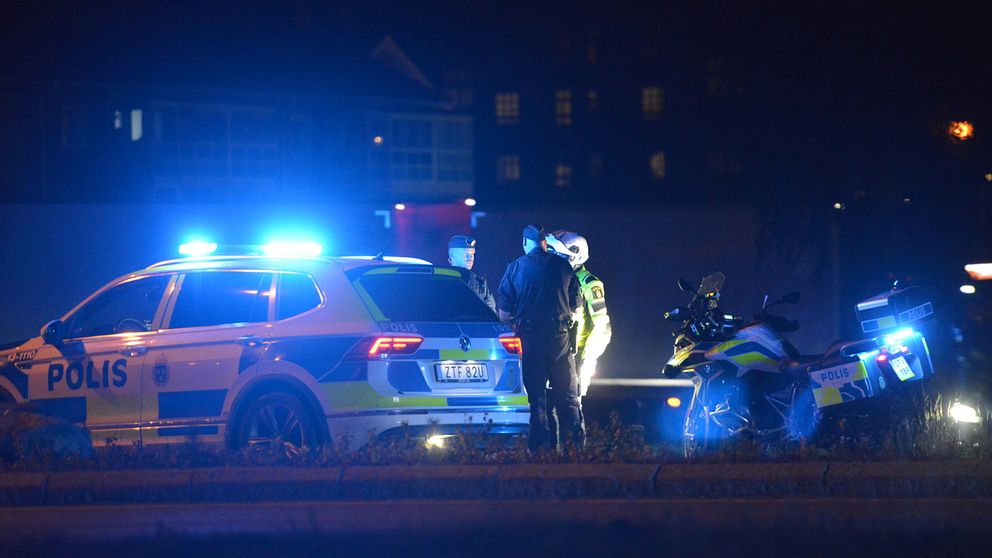 En polis, en polisbil och en mc-polis i kvällsmörkret under en insats i Timrå.