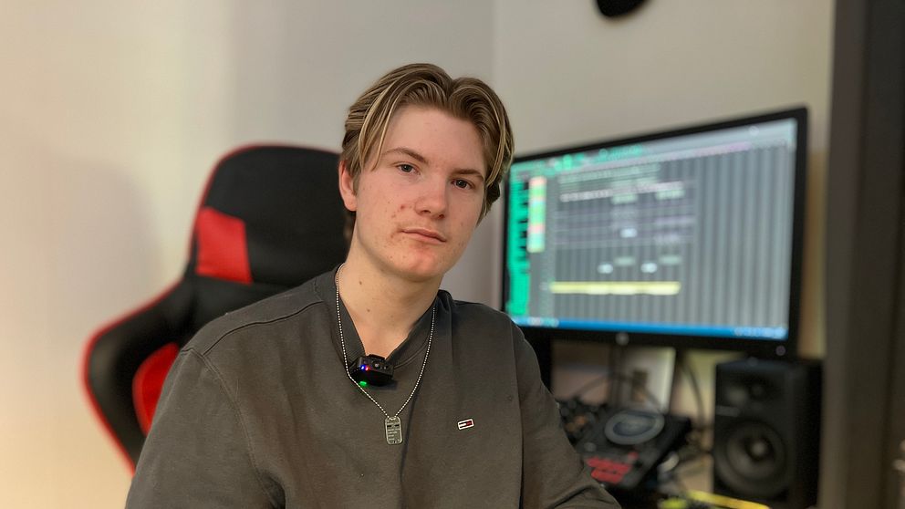 Person i inspelningsstudio med dator och ljudutrustning i bakgrunden.