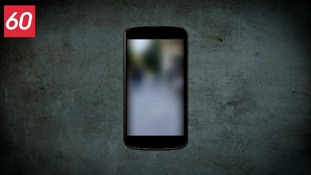 En mobil ligger på ett betonggolv, på skärmen visas en suddig video