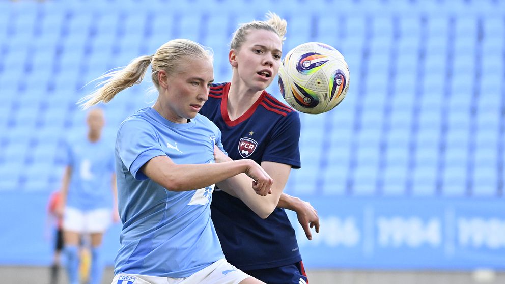 Två fotbollsspelare tävlar om bollen på plan.