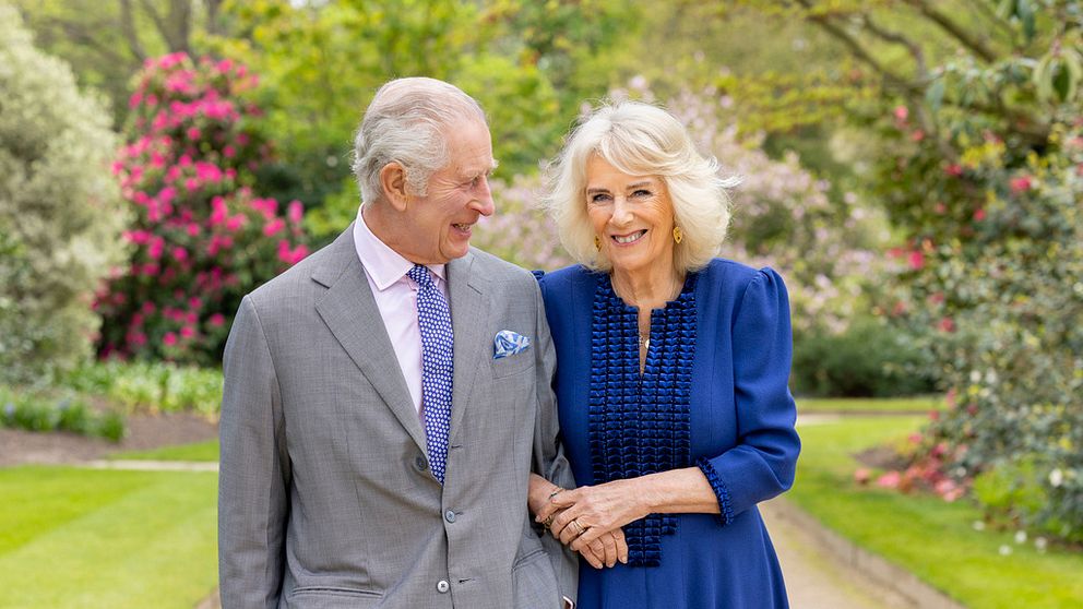 Kung Charles och drottning Camilla fotograferade i en trädgård.