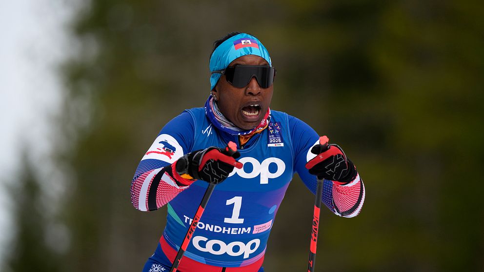 Skidåkare i blå tävlingsdräkt från COOP i full fart i skidtävling.