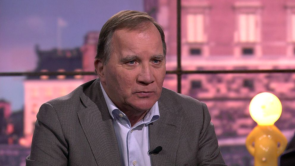Stefan Löfven i grå kavaj intervjuas i tv-studio med stadsmiljö i bakgrunden.