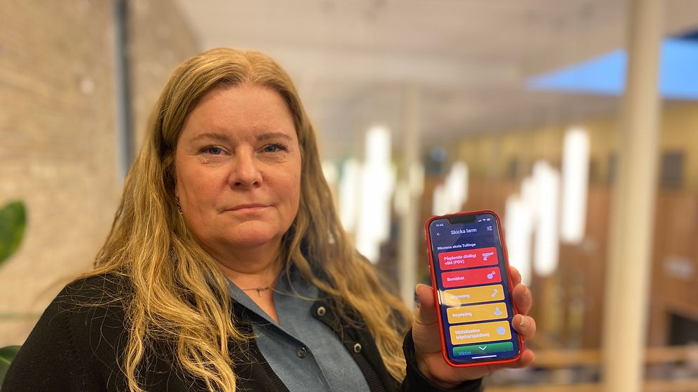 En kvinnlig rektor med en mobil sin hand.