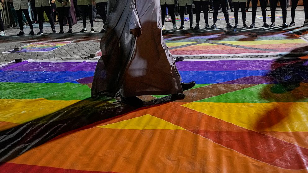 Människor kliver över en regnbågsflagga