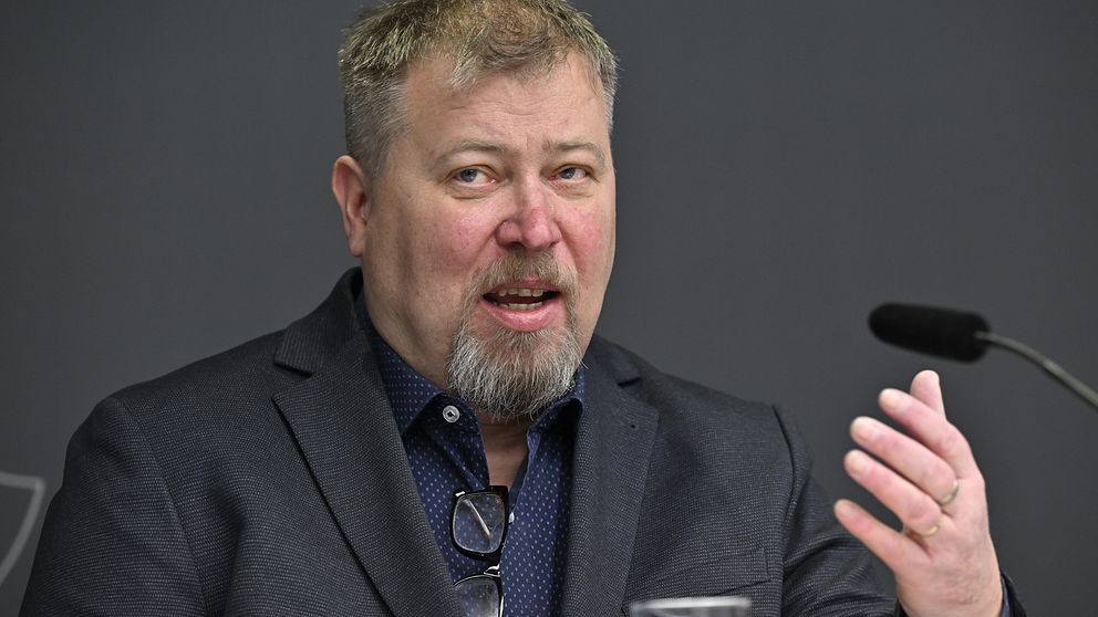Professorn i förvaltningsrätt Olle Lundin på en presskonferens med en mikrofon framför sig.