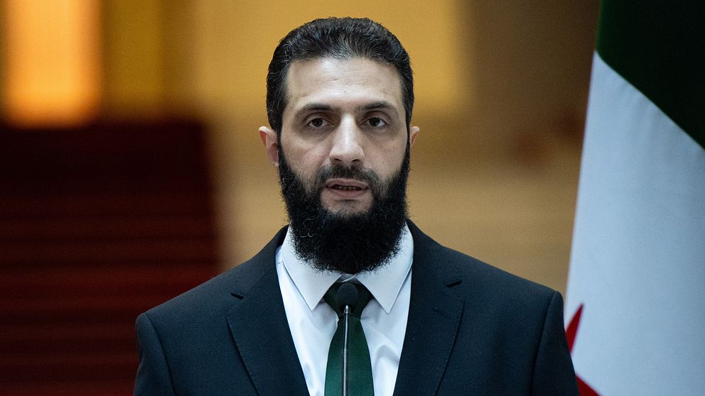 Syriens nya ledare AZhmad Al-Sharaa i mörk kostym och vit skjorta vid en pressträff i Damaskus.