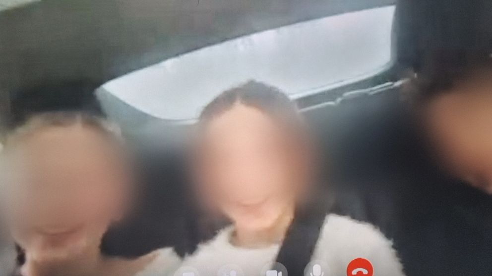Tre personer sitter i baksätet av en bil med regniga eller dimmiga bakgrundsvyer genom bilfönstret.