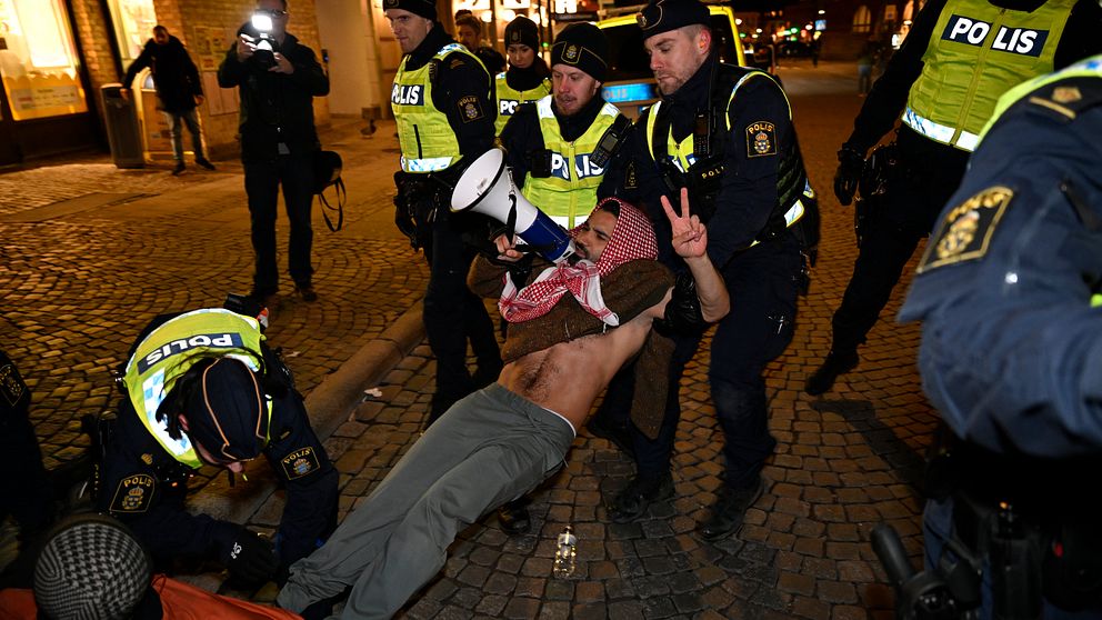 demonstrant med megafon förs bort av polisen på Stortorget i Lund