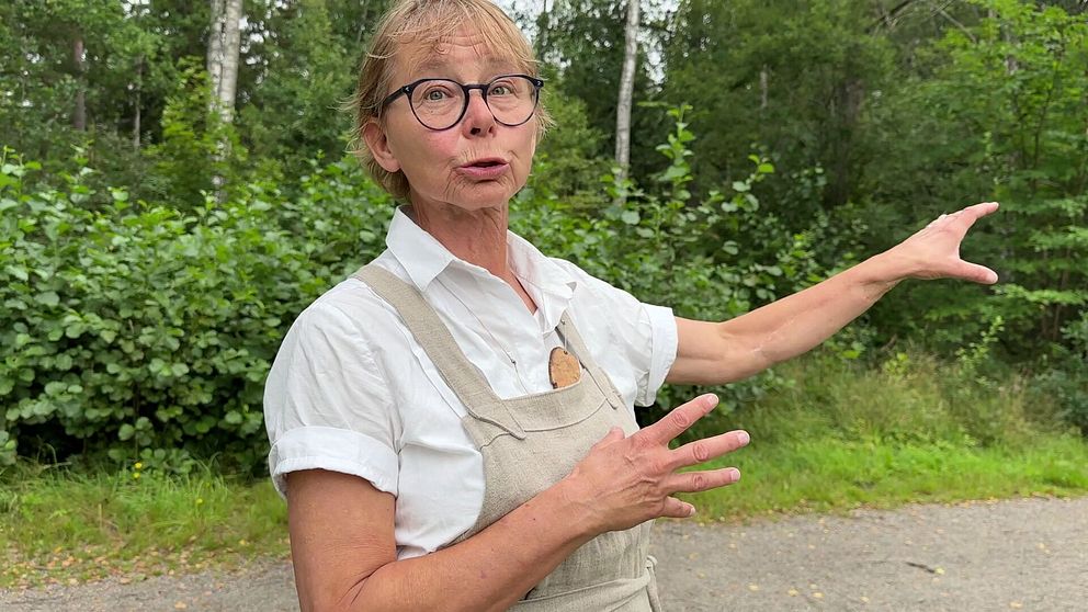 Margareta Edström pekar mot skogen som Strängnäs stift vill avverka.