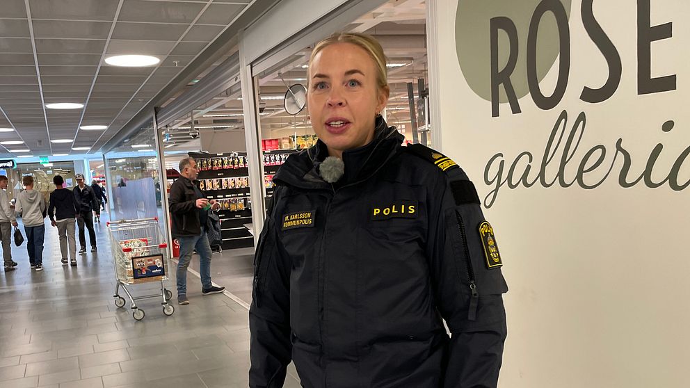 En kvinnlig polis står i ett köpcenter
