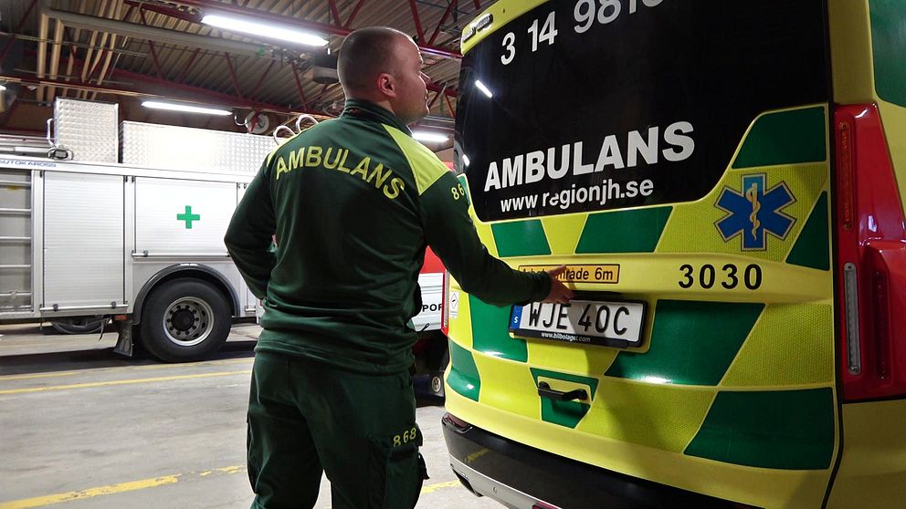 En ambulanssjuksköterska är på väg att öppna bakluckan till en av region Jämtland Härjedalens ambulansbilar i ett garage.
