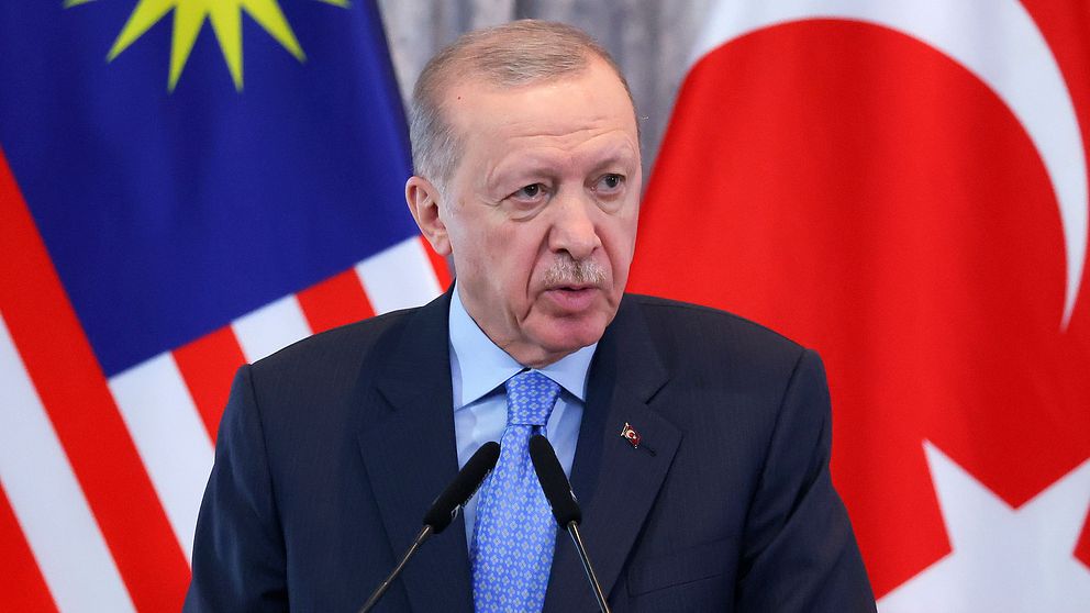 Två flaggor, Malaysias och Turkiets, bakom talare vid podiet.