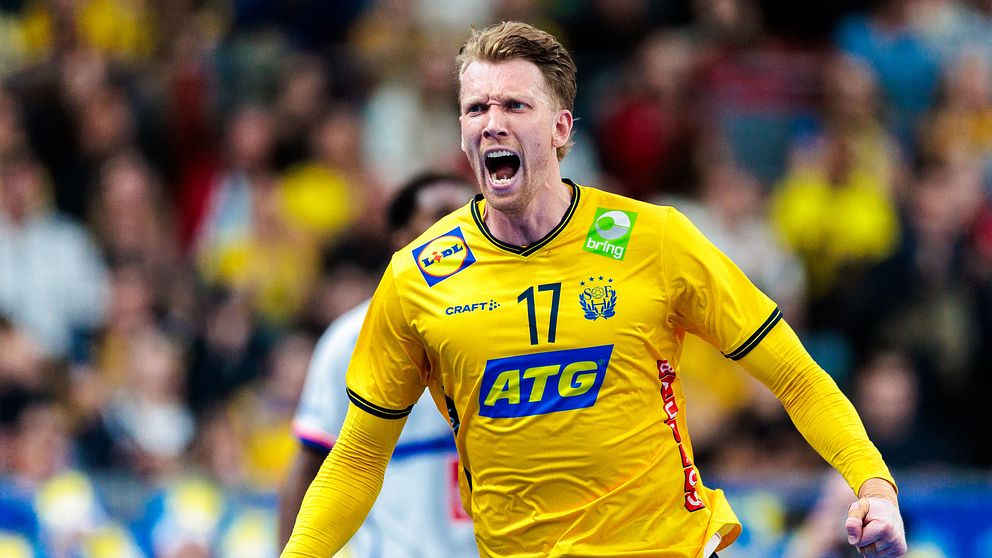 Handbollsspelare i Sveriges gula landslagströja under match med publik i bakgrunden.
