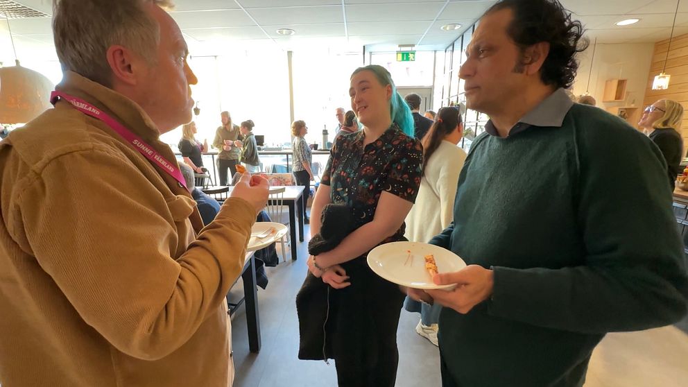 En grupp människor samtalar i en livlig kafémiljö.