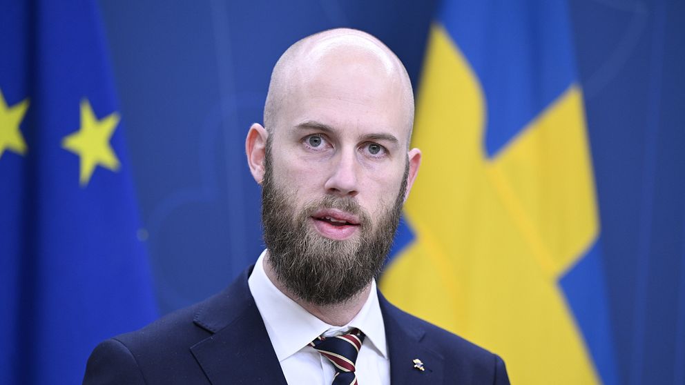 Carl-Oskar Bohlin (M) framför en Sverigeflagga på en pressträff.