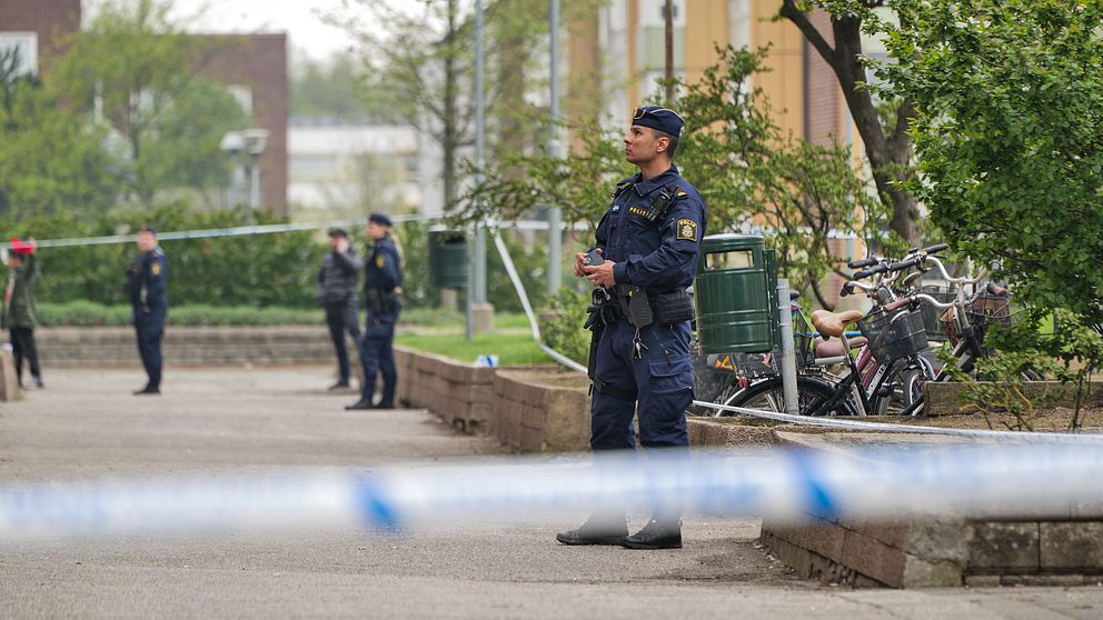 Poliser bevakar ett avspärrat område utanför ett bostadshus.