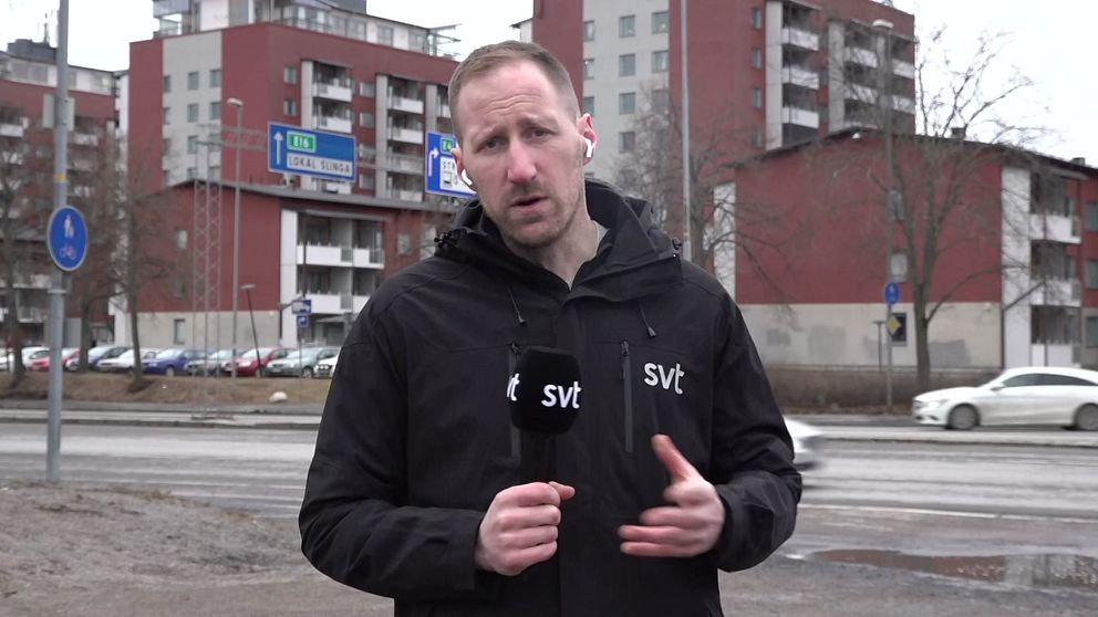 Reportern Arvid Jansson står framför flerfamiljshus och håller en SVT-mikrofon.