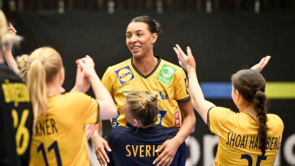 Handbollsspelare i gula tröjor firar och sträcker armarna mot en lagkamrat.